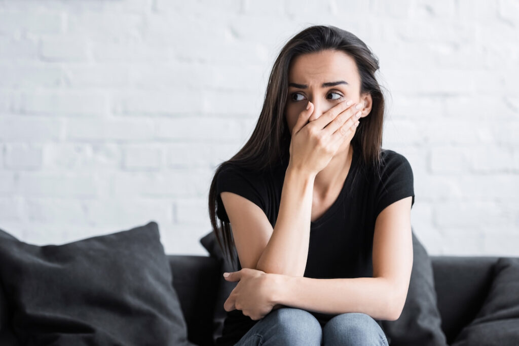 a scared woman holding a hand over her face