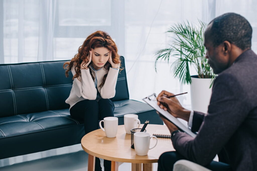 Upset young woman on couch and psychotherapist