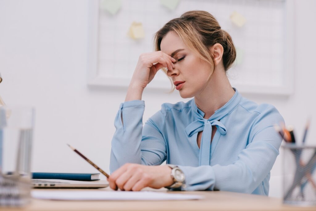 Exhausted adult businesswoman sitting at workplace in office