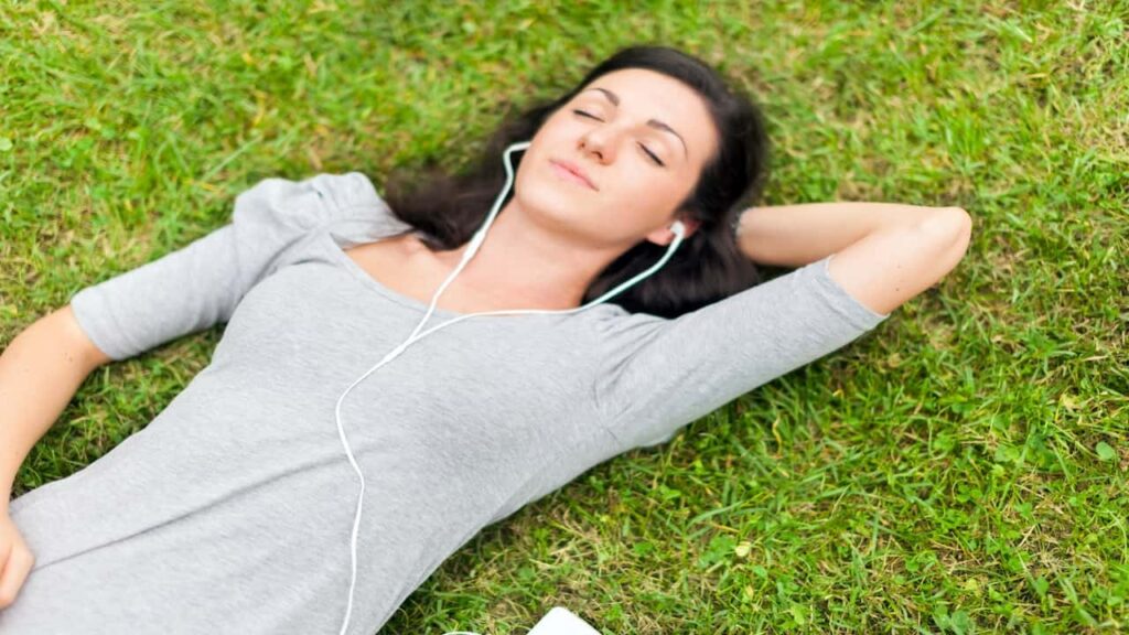 a woman lying on the grass with earphones