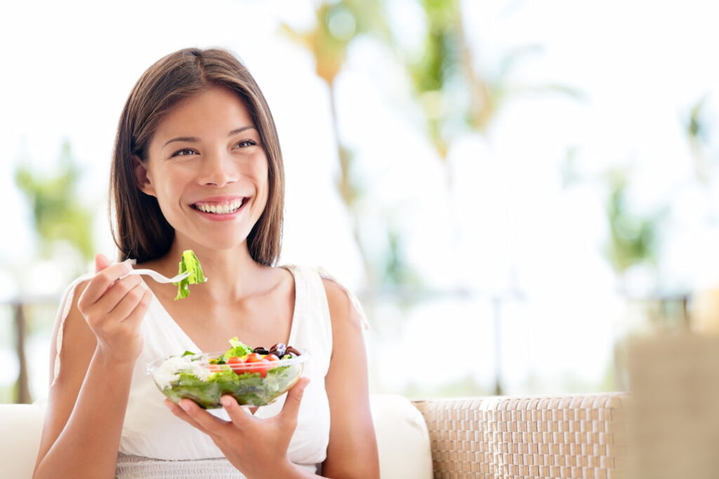 a young smiling woman eating healthy food