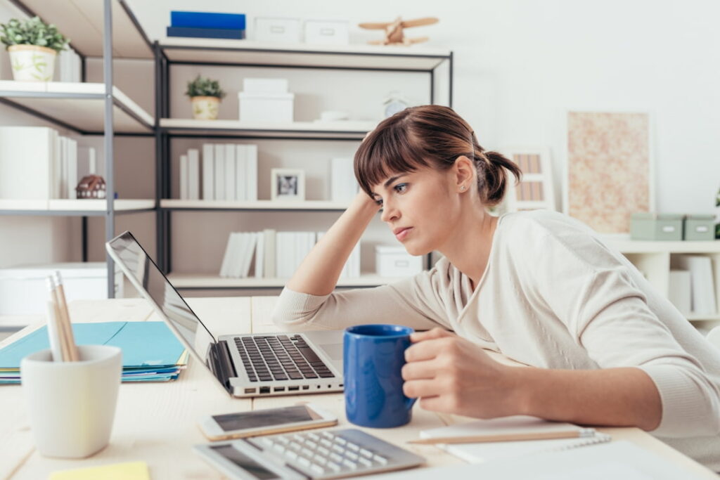 a tired woman looking at her laptop