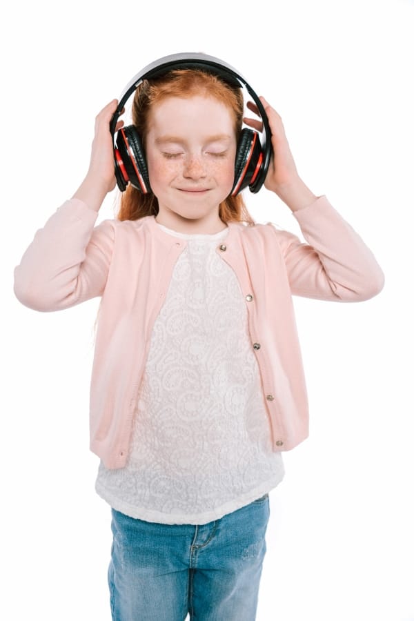 a girl with her eyes closed holding headphones on her head