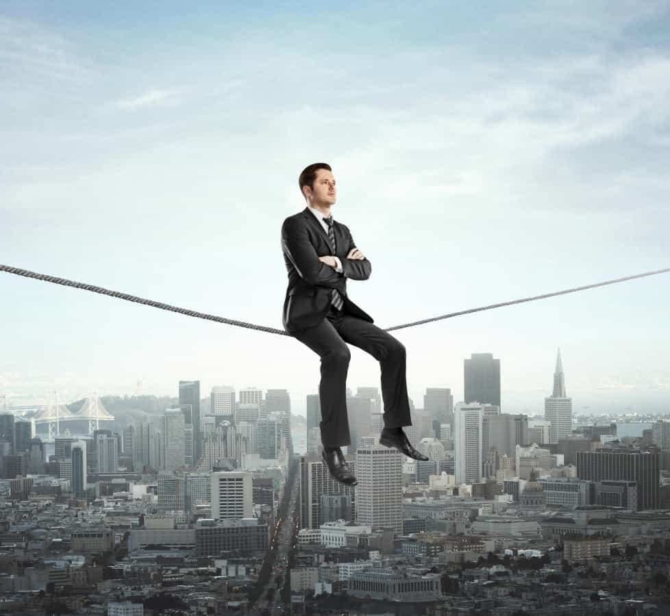 a man in a suit sitting on the rope above the city