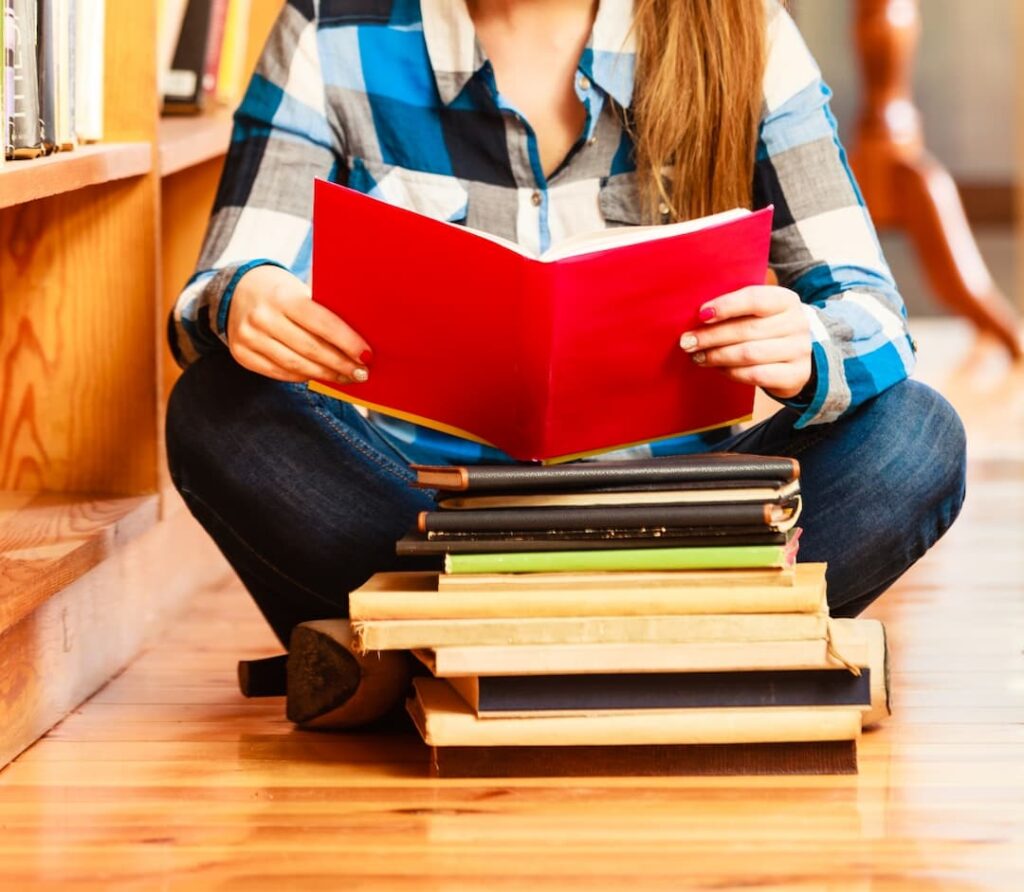 a female person sitting on the floor and reading a book