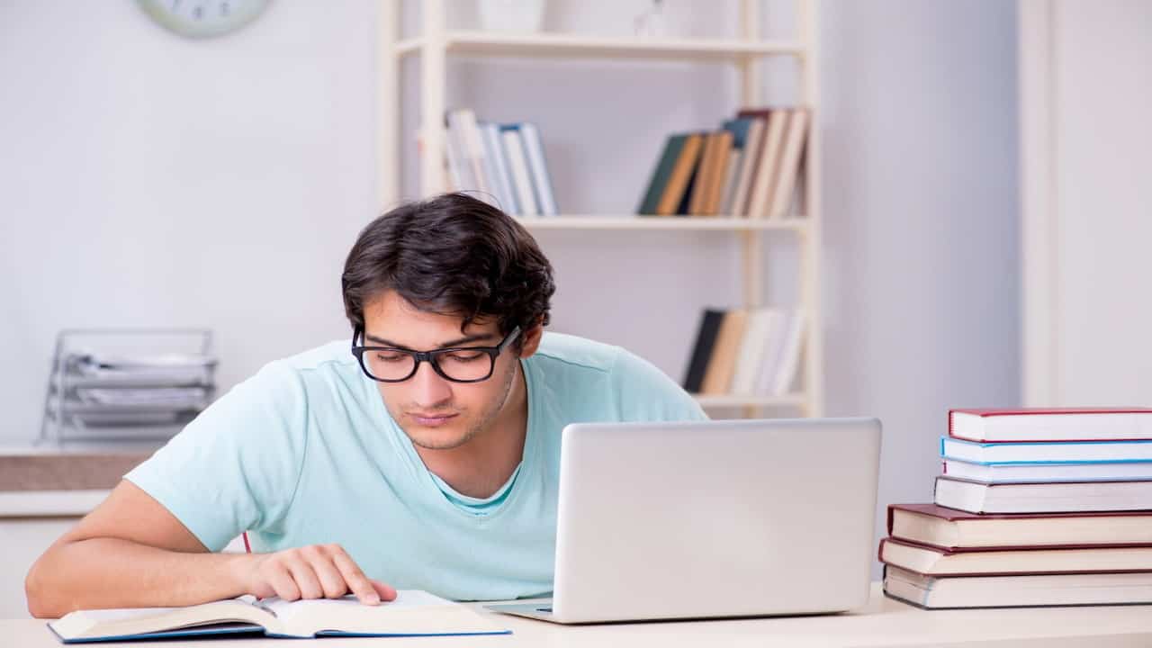 a young man studying with books and laptop
