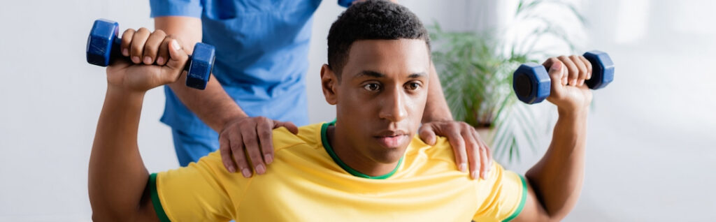 young athlete with weights and his therapist