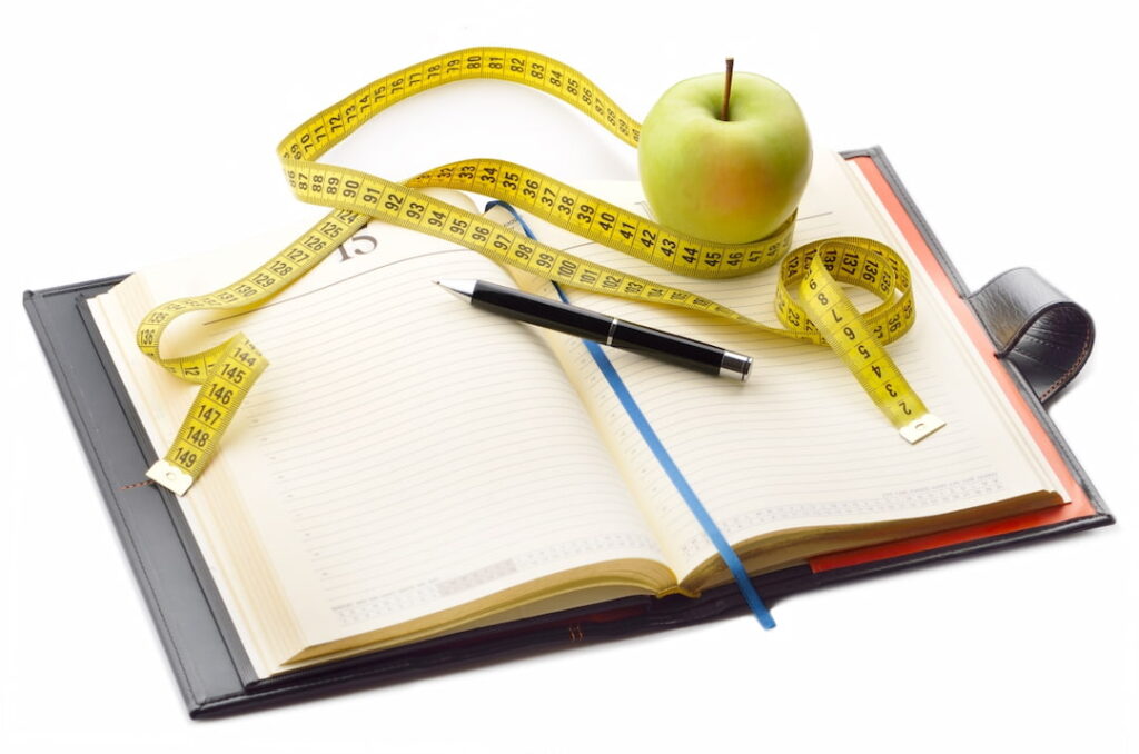 an apple, a pencil and a food diary