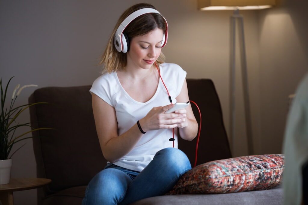 a woman with headphones and mobile phone sitting on the sofa