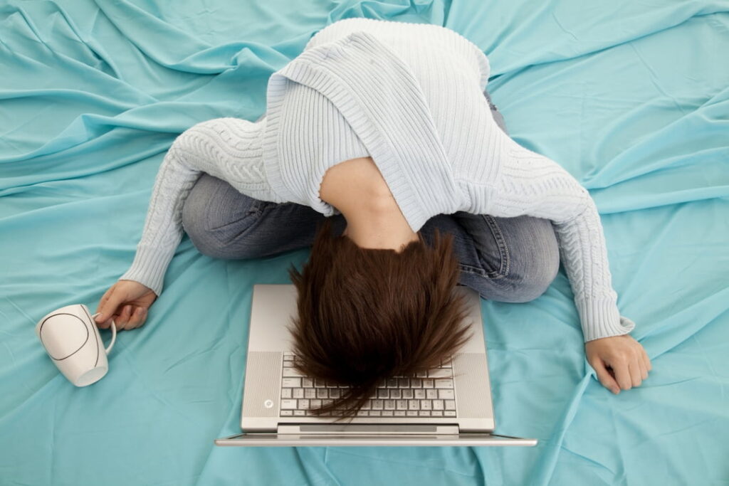 a woman on the bed sleeping with her head on the laptop