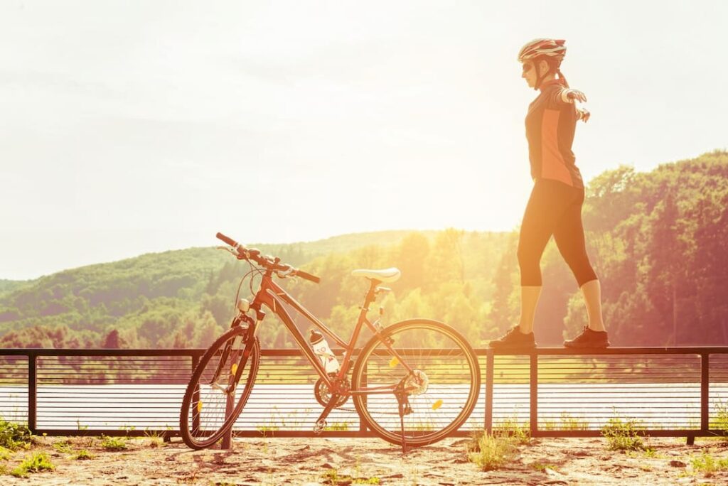 woman standing on the fence by her bicycle 