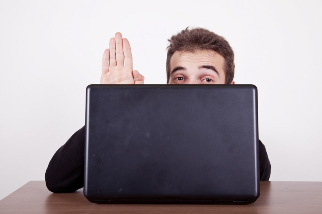 a man hiding behind the opened laptop