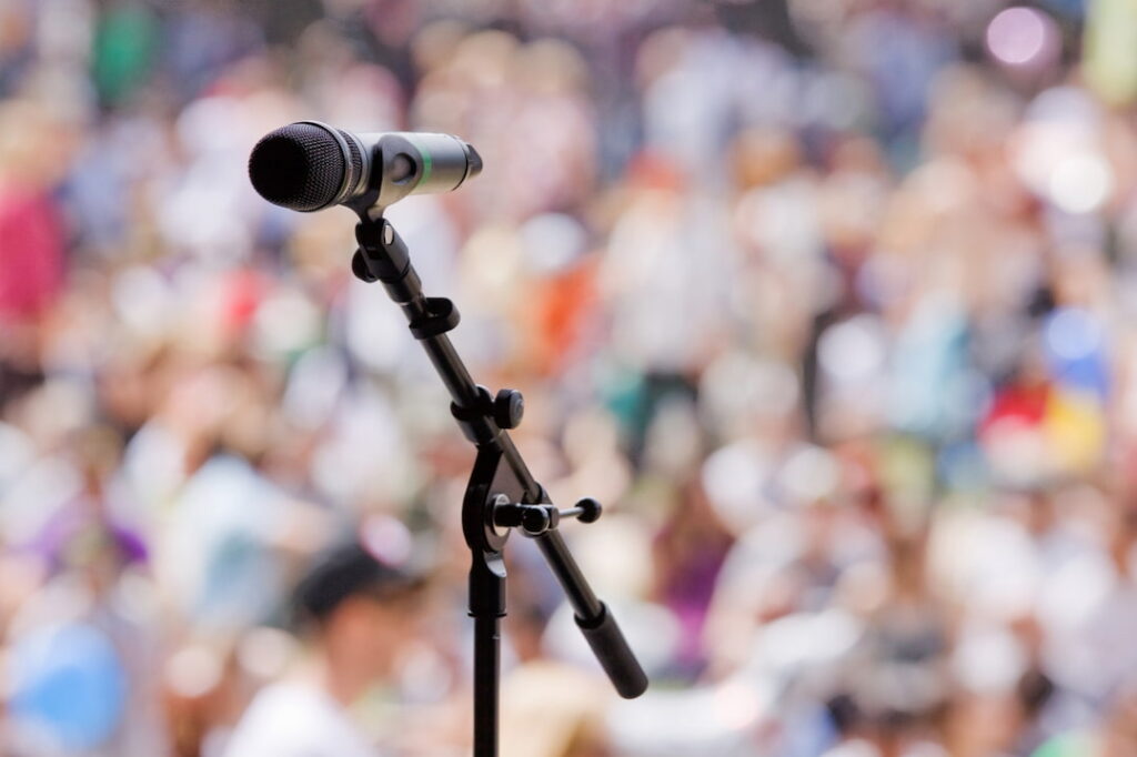 an open microphone with a crowd audience in the background 