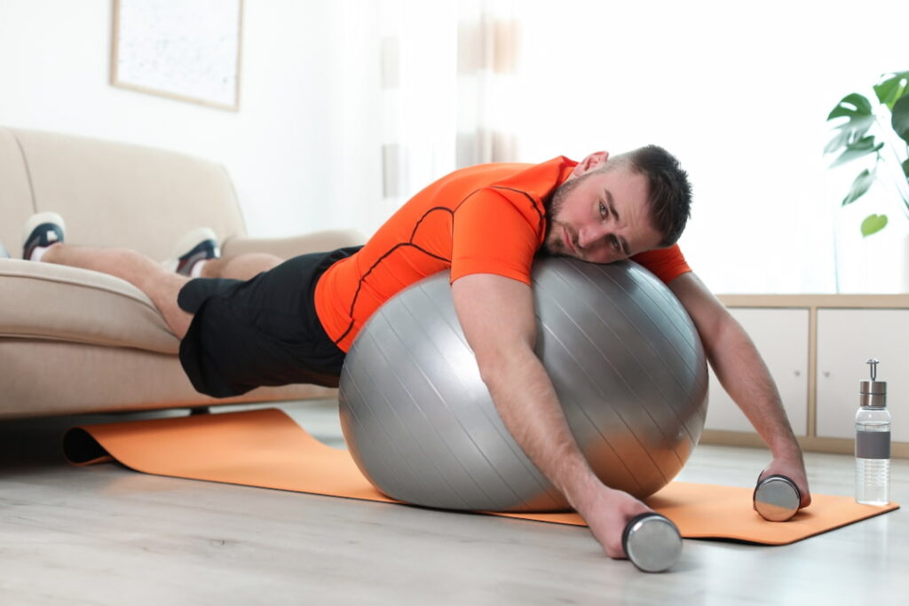 Demotivated young man with sport equipment at home