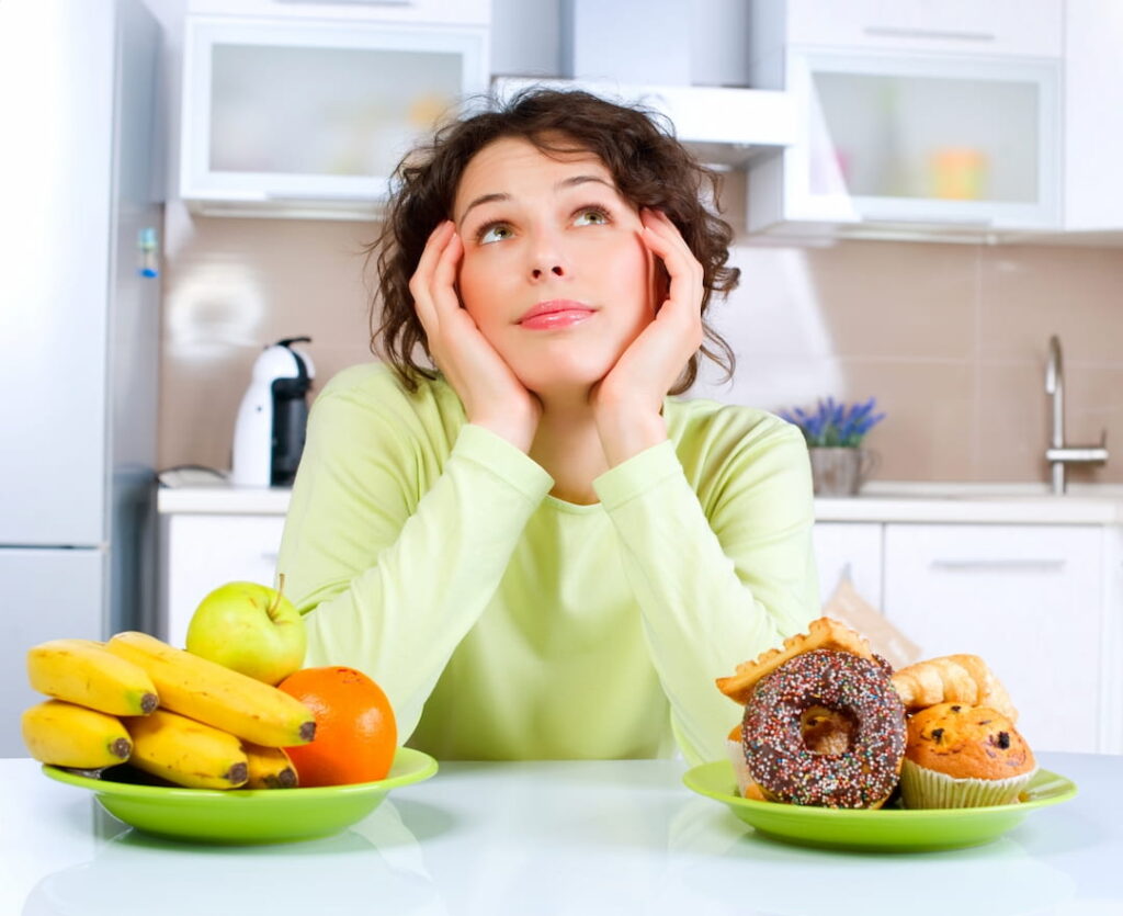 a woman thinking over the plates with fruits and sweets on the table