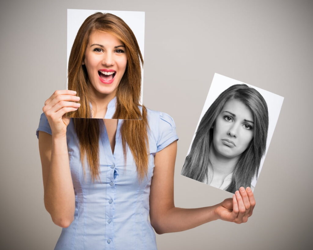 a women holding a happy picture and a sad picture