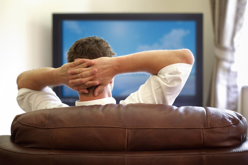 a man sitting in the armchair and watching tv 