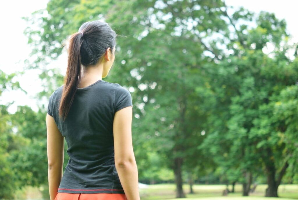 a woman standing outdoors and looking at the green trees