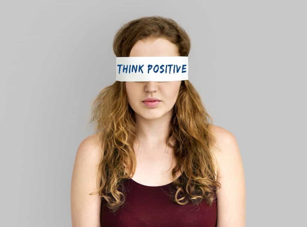 a woman with covered eyes with Think Positive note