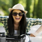 happy woman with hat and sunglasses riding the bicycle