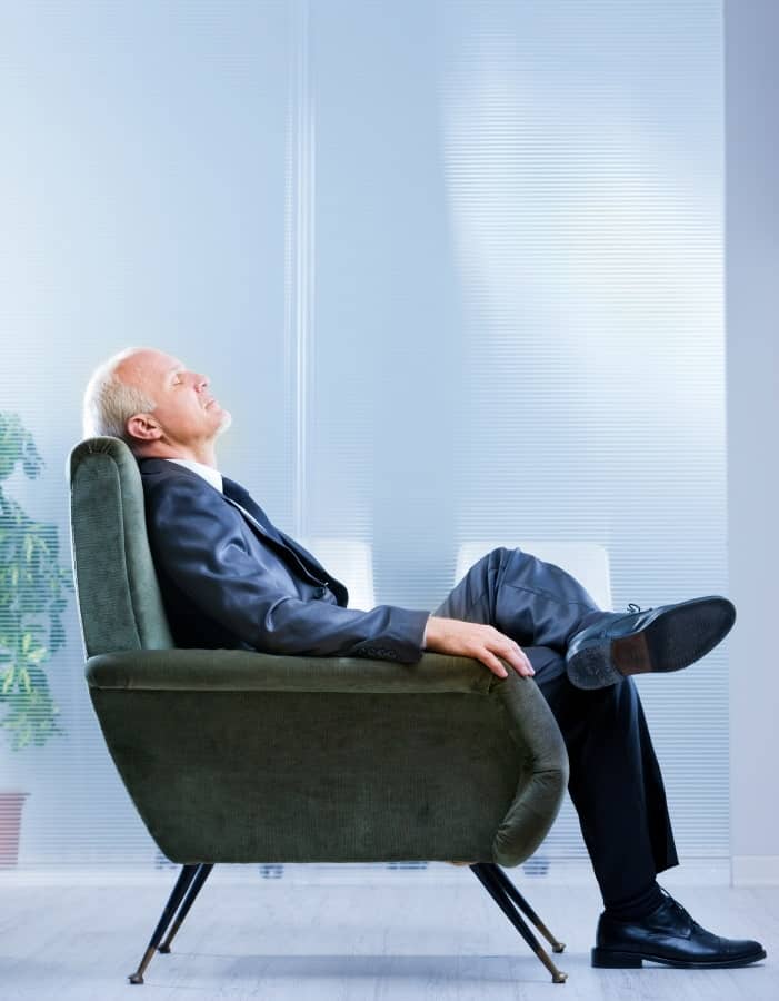 a man sitting in an armchair with his eye closed