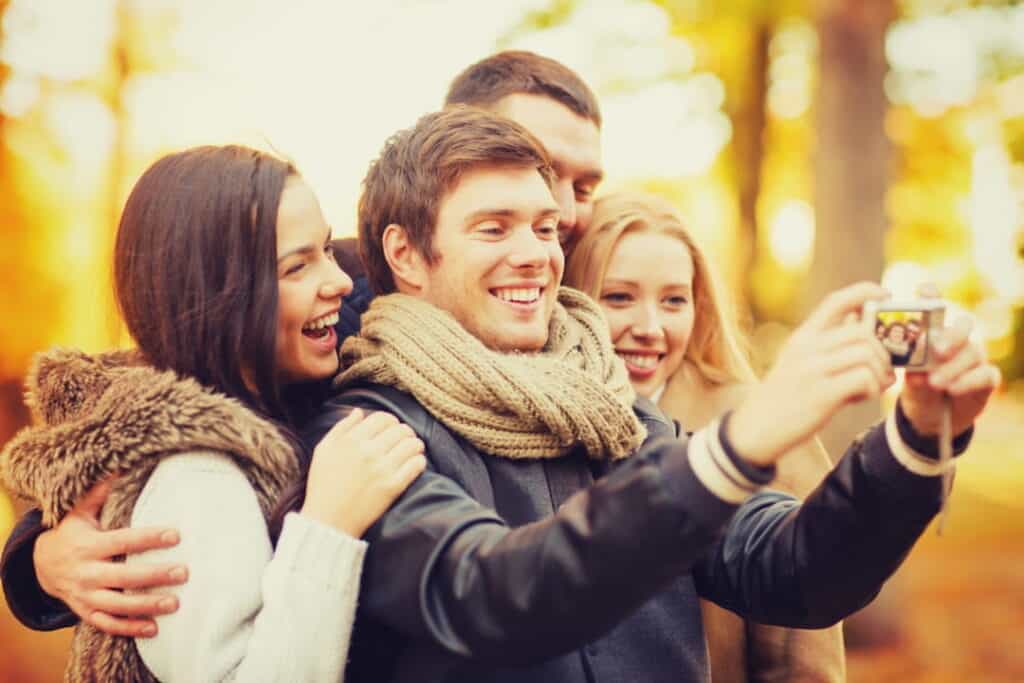 a group of friends with photo camera in autumn park