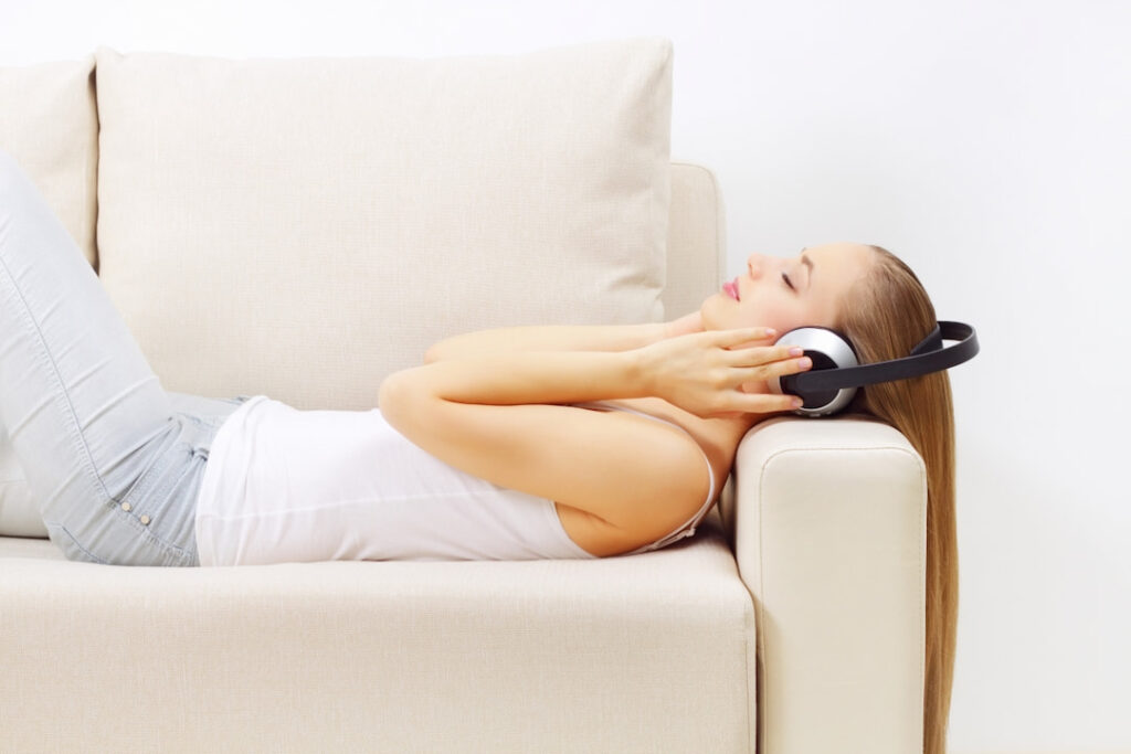 a girl lying on the couch with headphones on her head