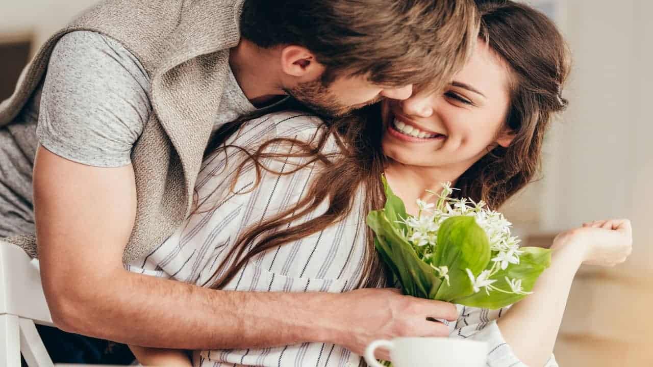 Young couple embracing with bouquet of flowers