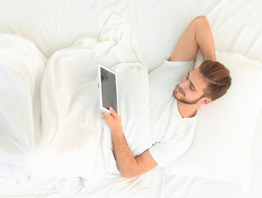 man in bed holding tablet