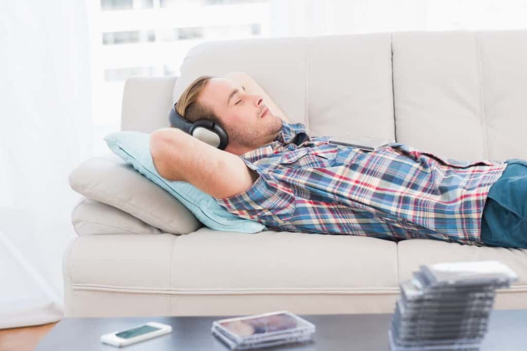 a man lying down on the couch and listening to hypnosis audios