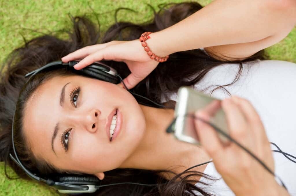 a woman lying down on the grass and listening to audios