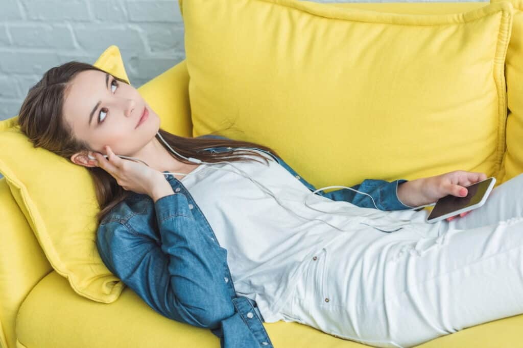 young woman lying on the couch and listening to audios