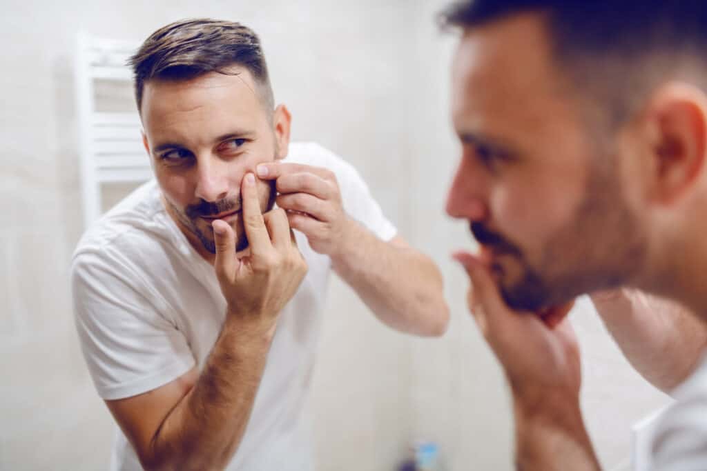 a man picking his face skin