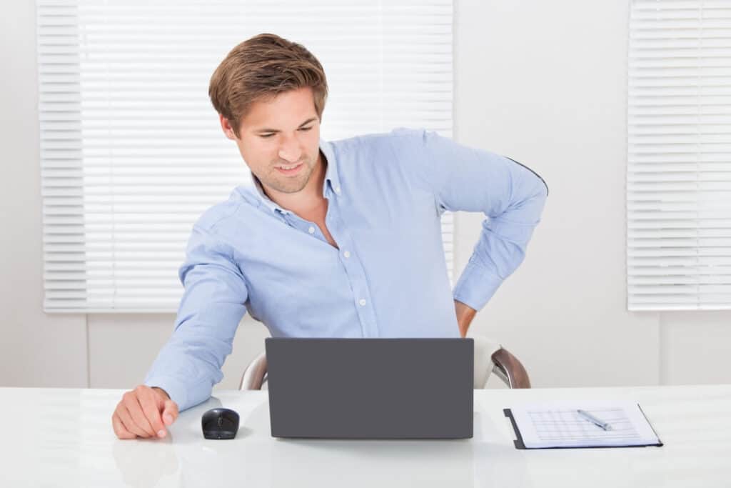 a man suffering from backpain sitting in the office