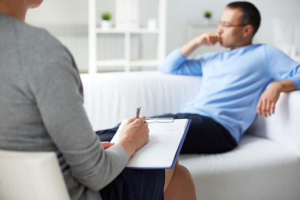 a man sitting on the couch at his hypnosis therapy session