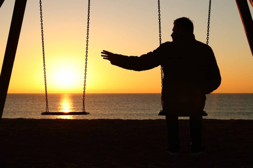 lonely man sitting on the swing by the sea