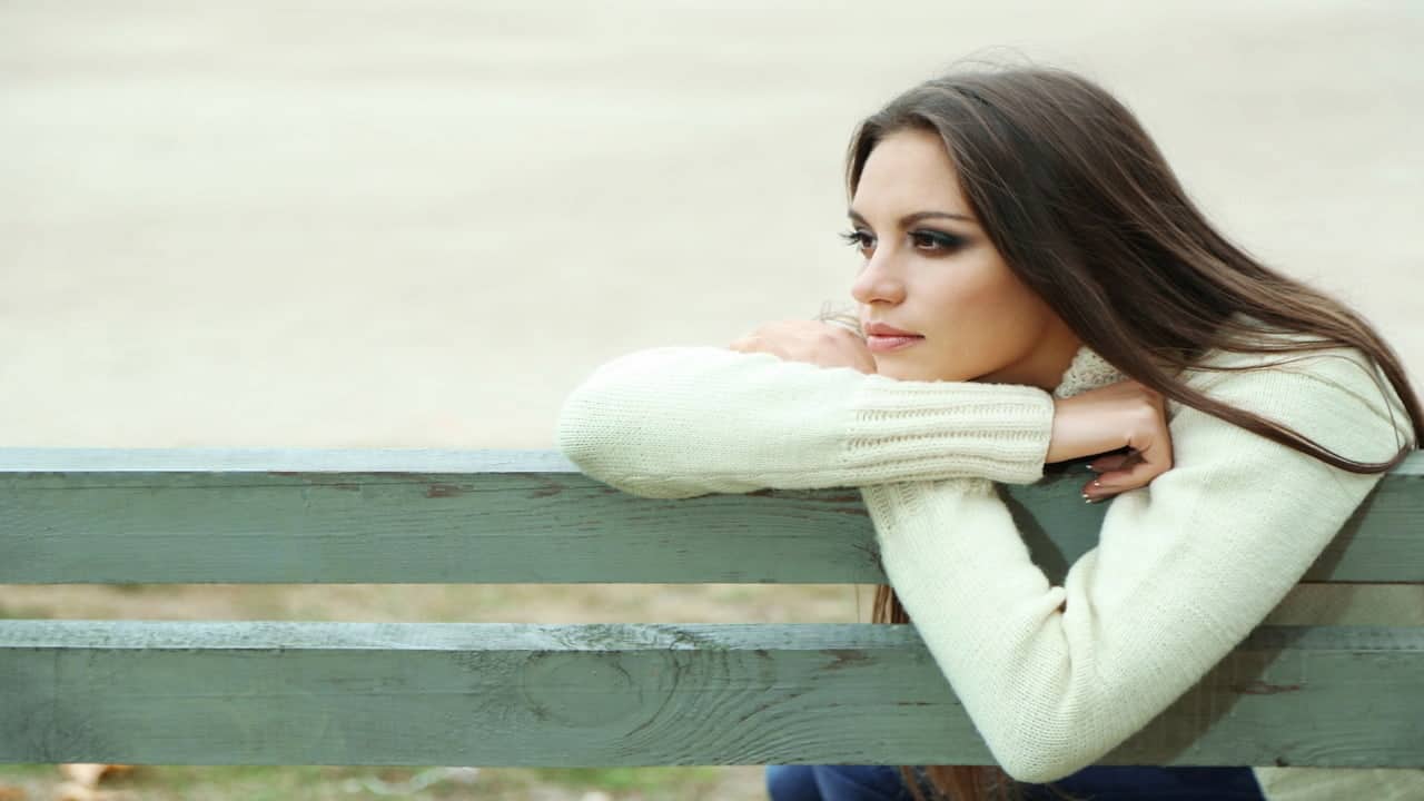 Young lonely woman sitting on the bench