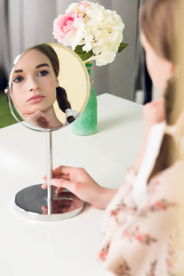 a young girl watching herself in the mirror