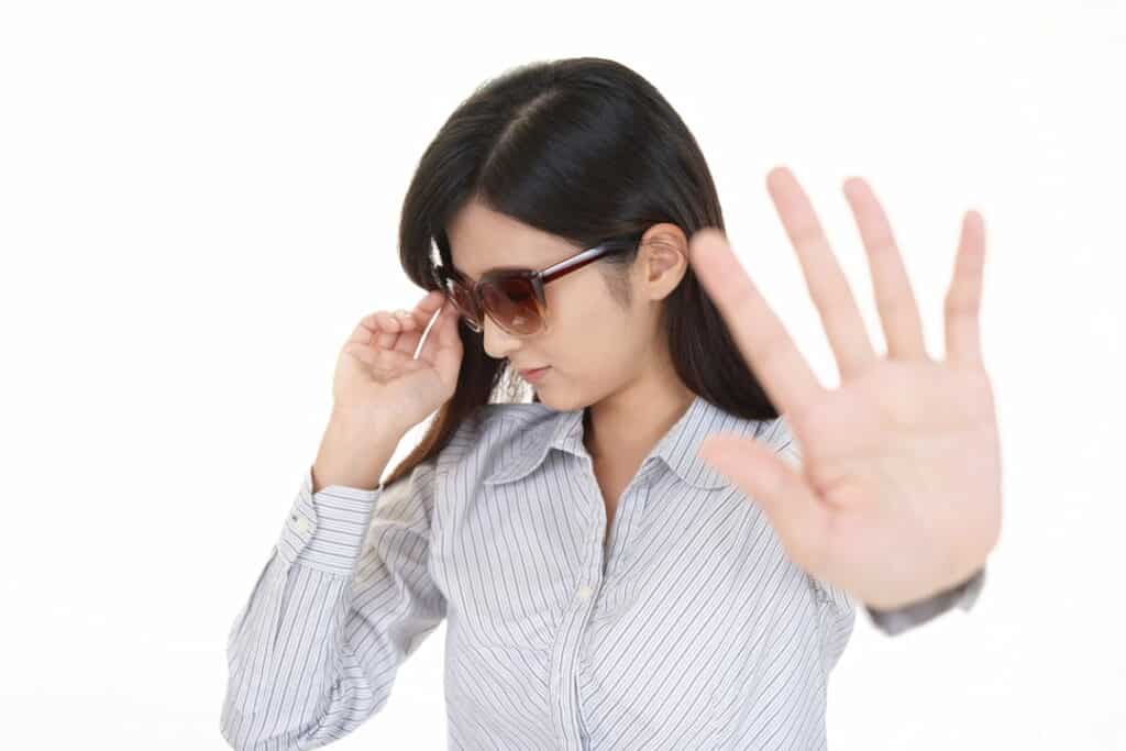 a woman with sunglasses showing stop hand gesture