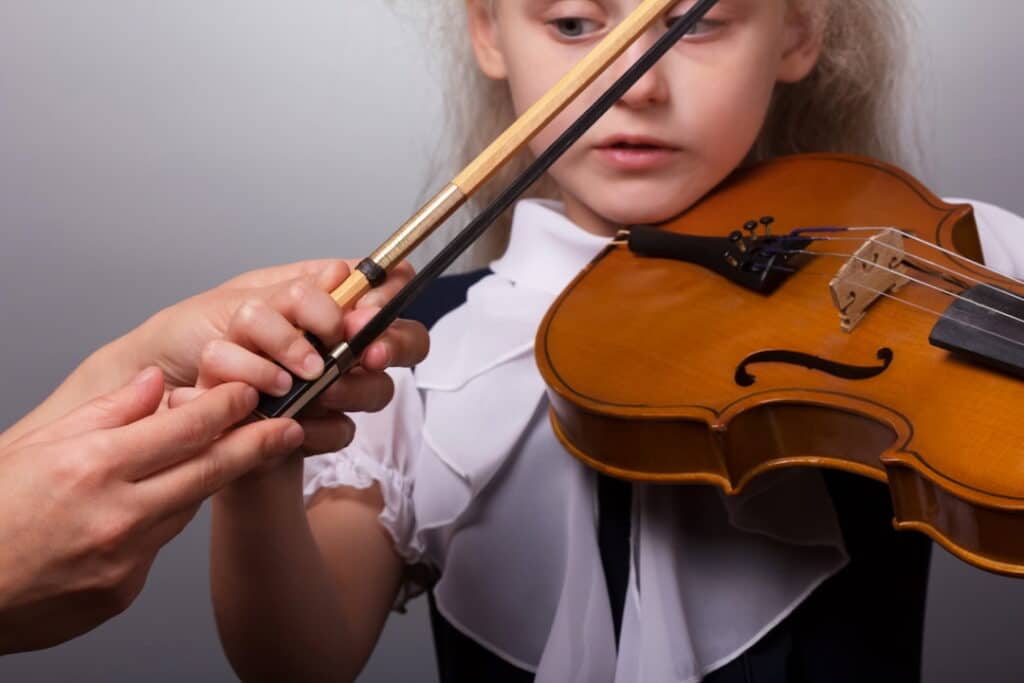 a teacher showing a little girl how to play the violin