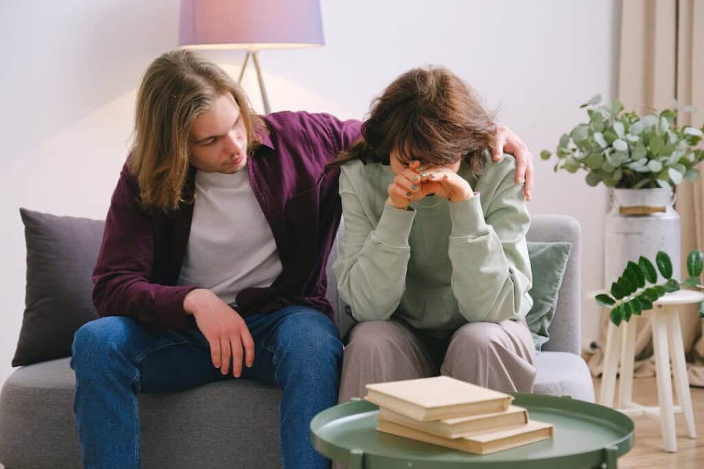 a sad young couple sitting on the sofa together