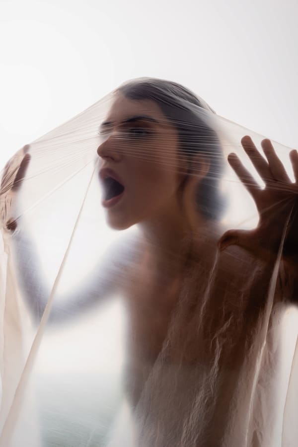 Young woman screaming through polyethylene