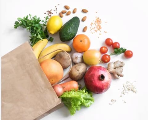 a paper bag with various fruits and vegetables