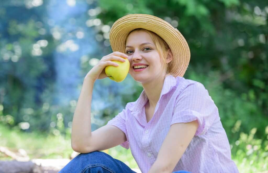 young woman with a hat eating an apple