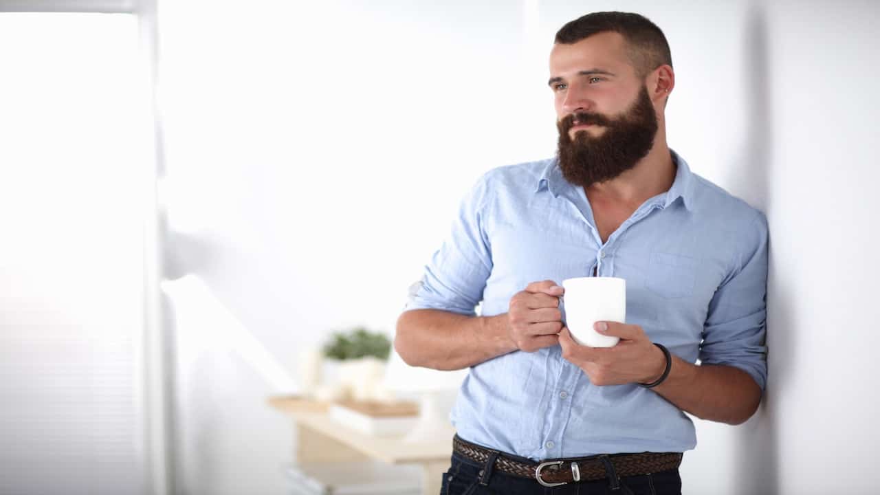 a young bearded man holding a cup of coffee