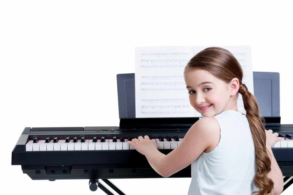 a smiling girl playing electric piano