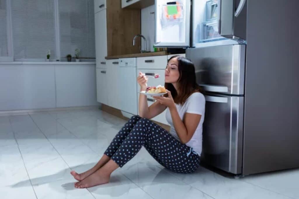 a woman eating in the kitchen at night