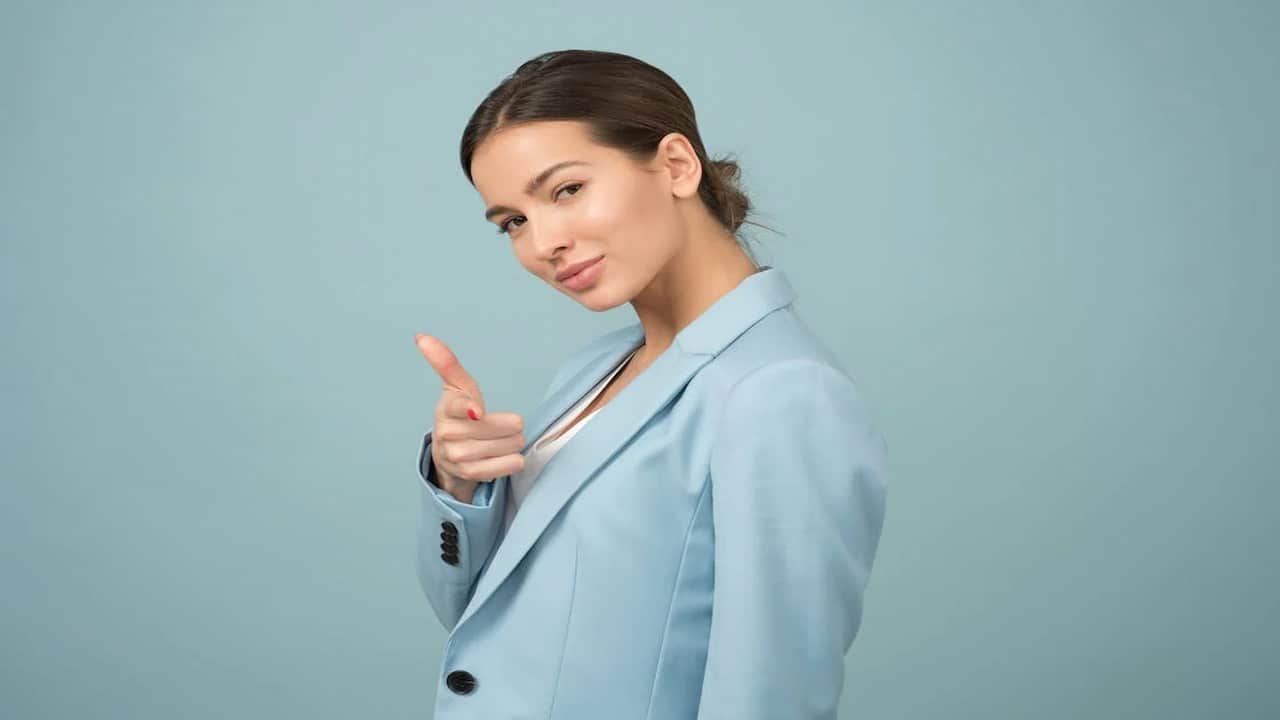 young woman in blue suit pointing with her finger to the camera