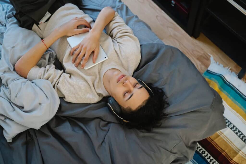 young man lying on the bed with tablet and headphones