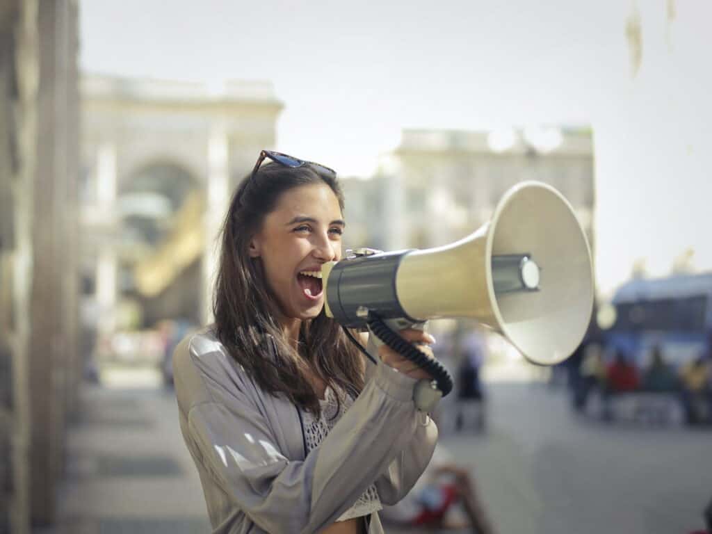 a woman outside speaking on a megaphone